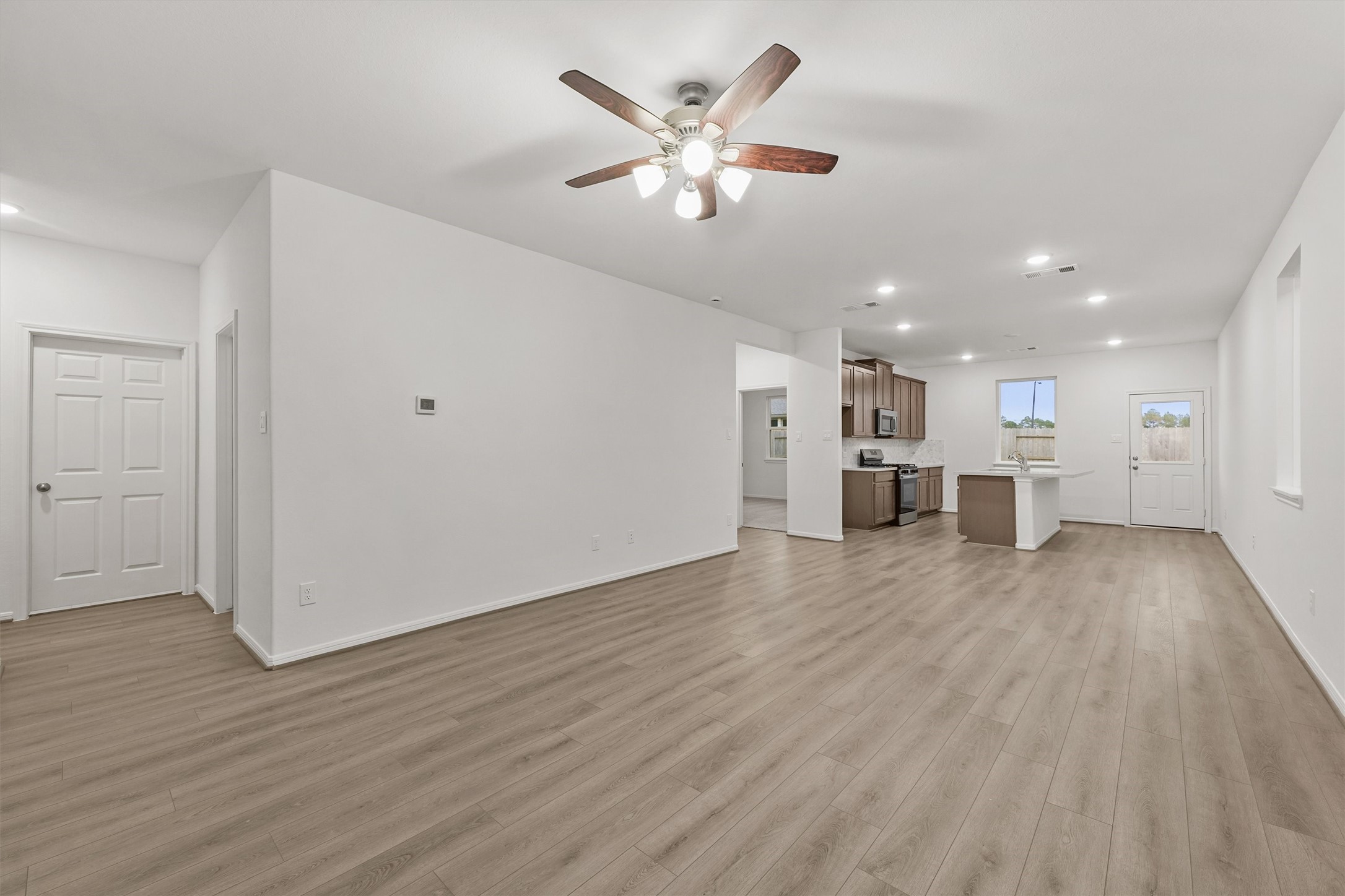 19111 Hazel Firs Court Magnolia, TX 77355 - Photo 12 of 34 a view of an empty room and kitchen with wooden floor