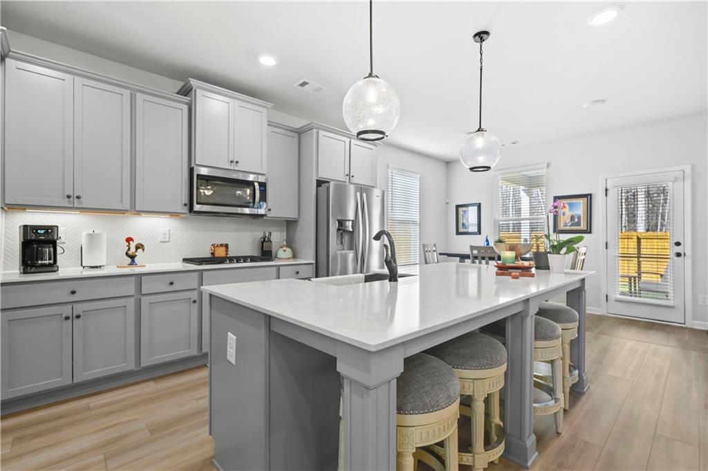 3258 Thicket Lane Atlanta, GA 30349 - Photo 7 of 38 a kitchen with stainless steel appliances kitchen island granite countertop a table chairs and a refrigerator