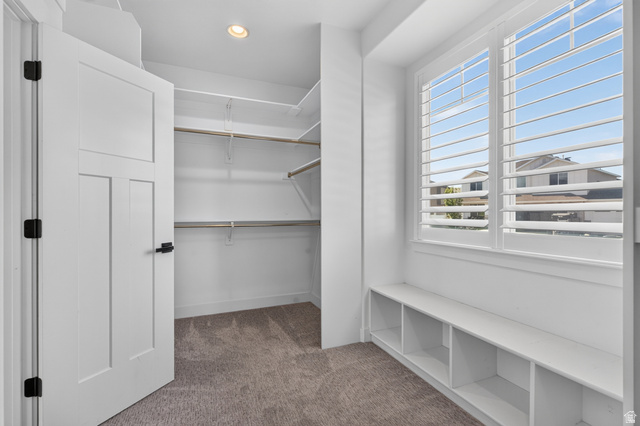 36 West Syracuse Road Vineyard, UT 84059 - Photo 32 of 56 Walk-in closet featuring carpet flooring, built-in shelving and hanging rods, a recessed ceiling light, and a window with plantation shutters and integrated storage bench