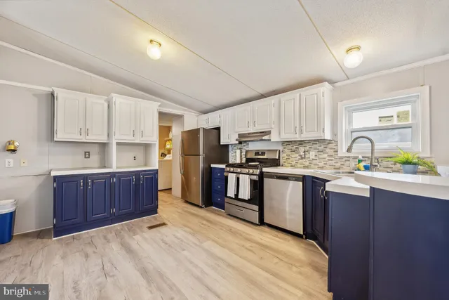 a kitchen with stainless steel appliances kitchen island granite countertop a stove refrigerator sink and cabinets