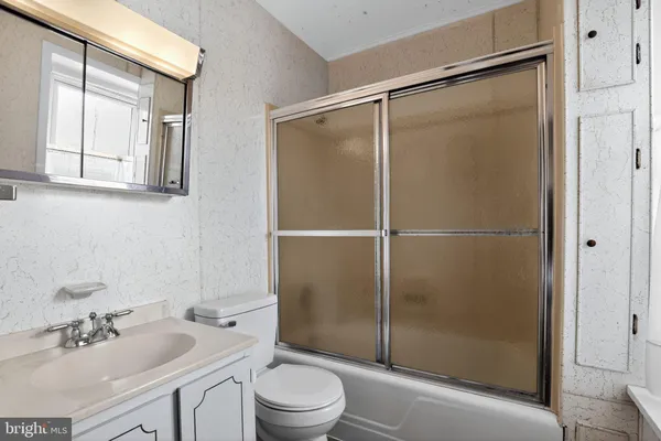 a bathroom with a shower sink vanity mirror and toilet