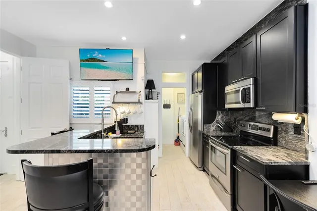 a kitchen with stainless steel appliances granite countertop a sink dishwasher stove and refrigerator with wooden floor