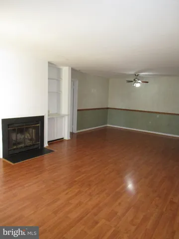 a view of an empty room with wooden floor and a fireplace