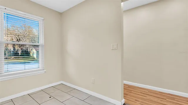 a view of an empty room with wooden floor and a ceiling fan