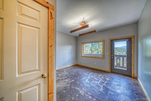 an empty room with windows and chandelier fan