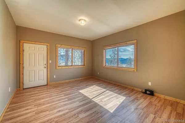 a view of an empty room with window and wooden floor