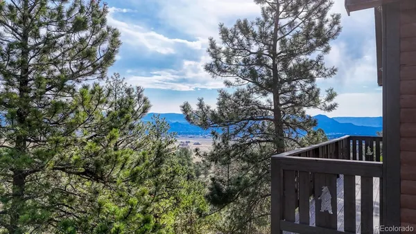a view of a wooden house with large trees and wooden fence