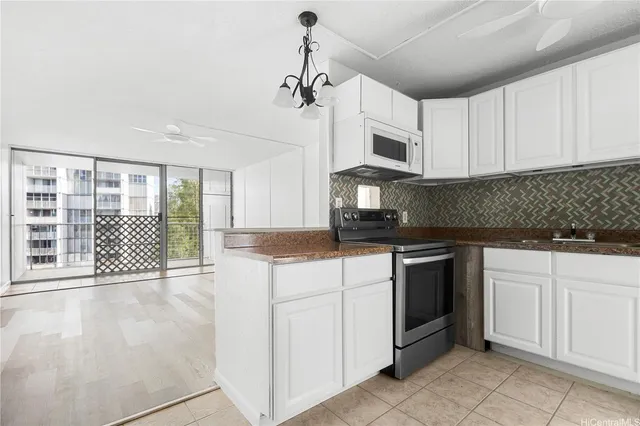 a kitchen with stainless steel appliances granite countertop a stove a sink and a refrigerator with white cabinets