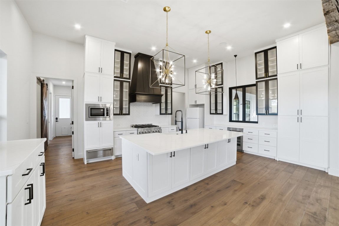 23937 Oscar Road Spicewood, TX 78669 - Photo 12 of 36 a large white kitchen with stainless steel appliances kitchen island granite countertop a stove a refrigerator a oven and a sink with large countertops