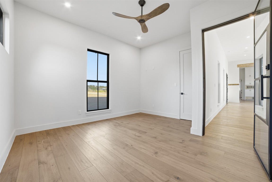 23937 Oscar Road Spicewood, TX 78669 - Photo 19 of 36 a view of an empty room with wooden floor and a window
