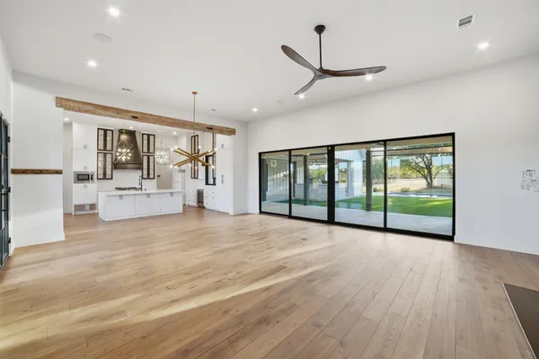 a large white kitchen with a large island oven a stove and a wooden floors