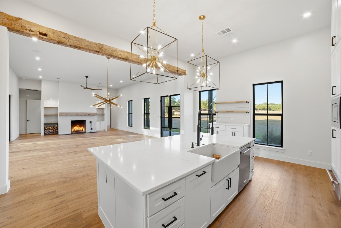 23937 Oscar Road Spicewood, TX 78669 - Photo 7 of 36 a large white kitchen with a large island oven a stove and a wooden floors