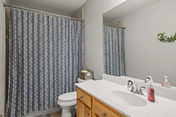 a bathroom with a sink a toilet and shower curtain