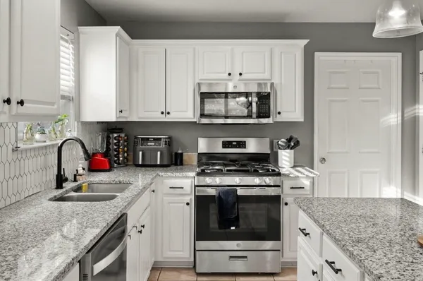 a kitchen with stainless steel appliances granite countertop a sink stove and cabinets