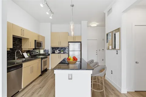 a kitchen with stainless steel appliances kitchen island granite countertop a refrigerator and a sink