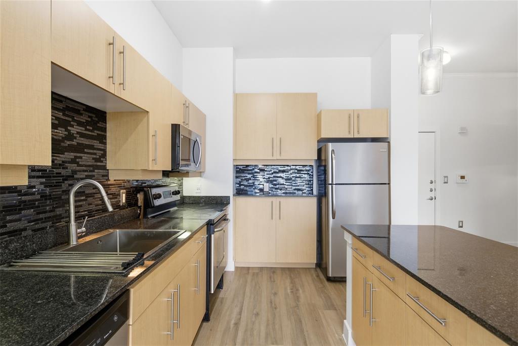 4414 Cedar Springs Road, Unit 312 Dallas, TX 75219 - Photo 24 of 30 a kitchen with kitchen island granite countertop a sink stove and refrigerator