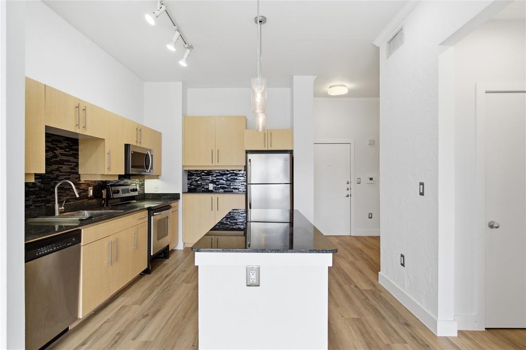 4414 Cedar Springs Road, Unit 312 Dallas, TX 75219 - Photo 25 of 30 a kitchen with stainless steel appliances granite countertop a refrigerator a stove and a sink with wooden floor