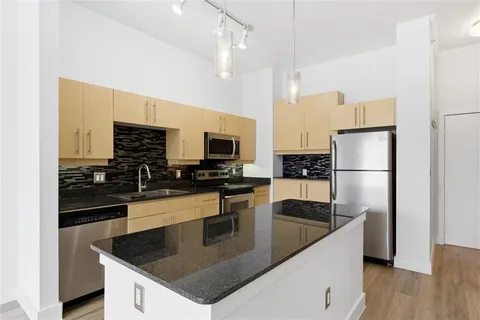 a kitchen with stainless steel appliances granite countertop a sink a stove and a wooden floors