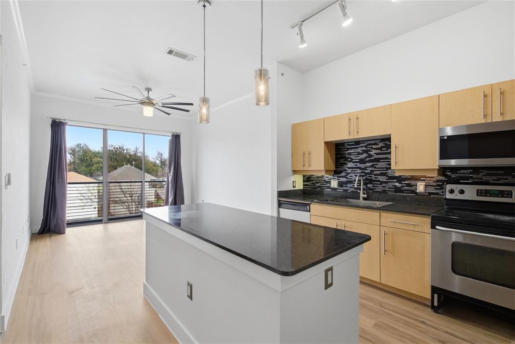 4414 Cedar Springs Road, Unit 312 Dallas, TX 75219 - Photo 27 of 30 a kitchen with stainless steel appliances granite countertop a sink a stove and a wooden floors