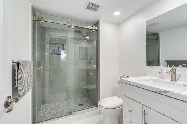 a bathroom with a shower sink vanity mirror and toilet