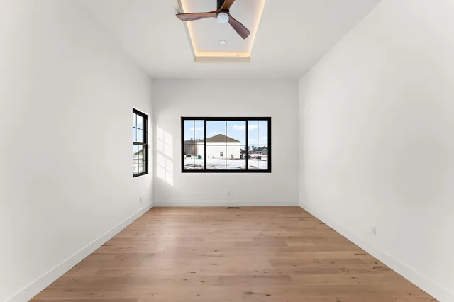 an empty room with wooden floor and windows