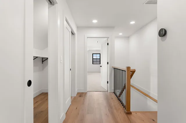 a view of a hallway with wooden floor and a bathroom