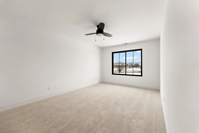 an empty room with windows and ceiling fan