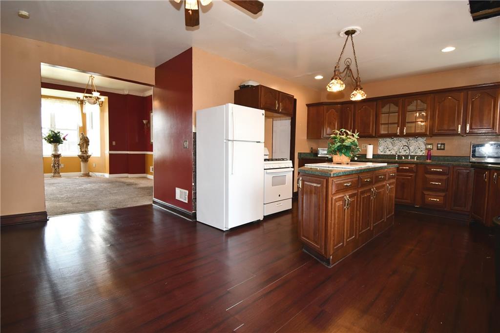 108 Locust Street Pittsburgh, PA 15210 - Photo 6 of 36 a kitchen with stainless steel appliances granite countertop a refrigerator a sink dishwasher a stove and a dining table with wooden floor