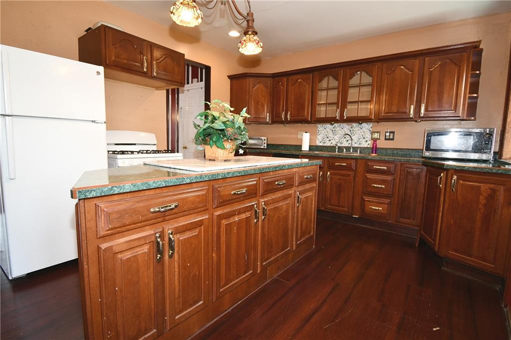 108 Locust Street Pittsburgh, PA 15210 - Photo 7 of 36 a kitchen with stainless steel appliances granite countertop wooden cabinets a stove a sink and dishwasher with wooden floor