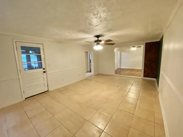 an empty room with wooden floor chandelier fan and windows
