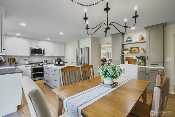 a kitchen with stainless steel appliances kitchen island granite countertop a sink a stove a refrigerator cabinets and chairs