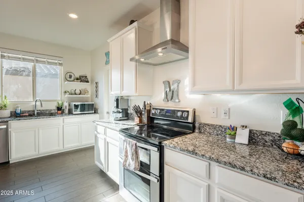 a kitchen with granite countertop a sink a stove and chairs