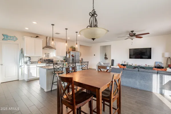a view of a dining room and livingroom with furniture wooden floor a rug a chandelier