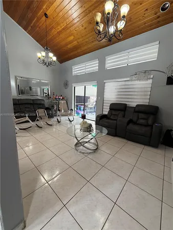 a living room with patio furniture and a chandelier