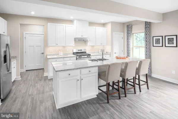 a kitchen with stainless steel appliances granite countertop a stove a sink dishwasher a microwave oven and a dining table with wooden floor