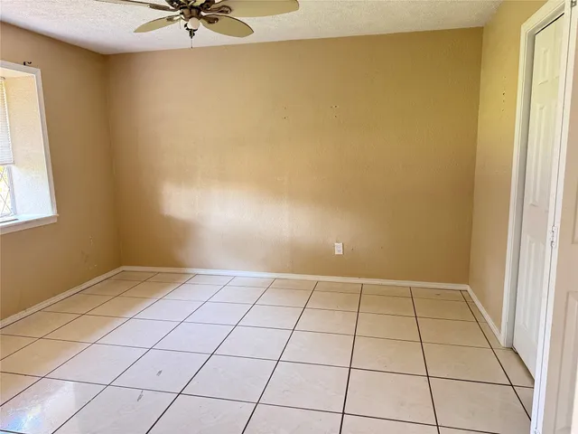a view of an empty room and window with a chandelier fan