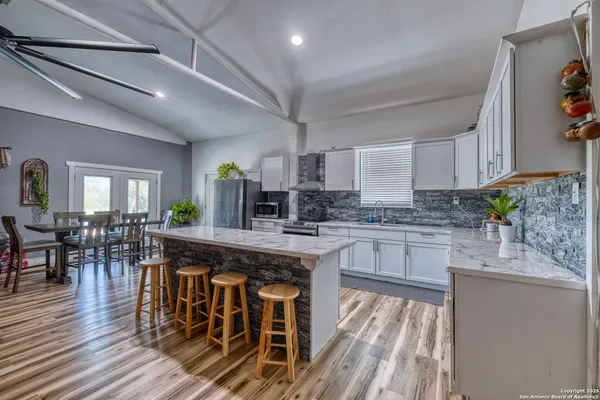 a kitchen with stainless steel appliances granite countertop a kitchen island a stove a table and chairs in it