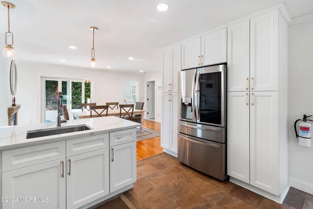 a kitchen with stainless steel appliances kitchen island granite countertop a refrigerator and a sink
