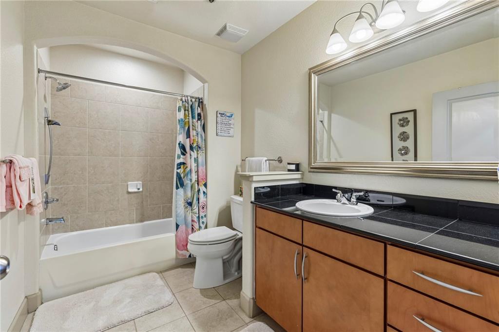 3445 Stratford Road Northeast, Unit 3105 Atlanta, GA 30326 - Photo 27 of 47 a bathroom with a granite countertop sink a toilet a mirror a vanity a shower and bathtub