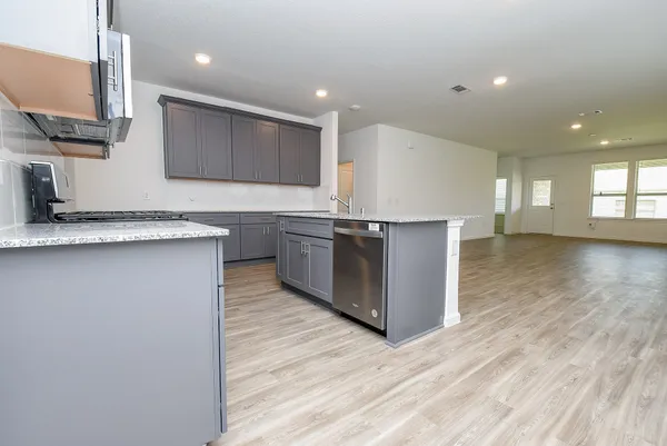 a kitchen with stainless steel appliances granite countertop a sink a stove top oven a counter space and cabinets