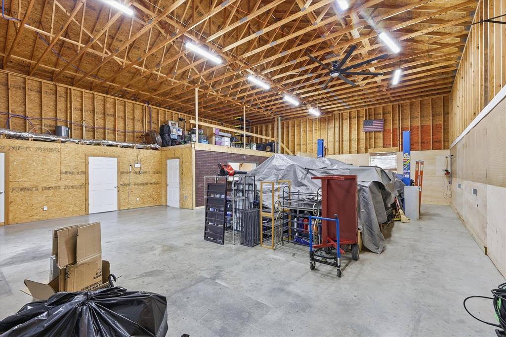 110 Highview Road Ennis, TX 75119 - Photo 29 of 40 Spacious industrial-style interior featuring high vaulted ceilings with exposed wood framing, concrete flooring, and ample fluorescent lighting