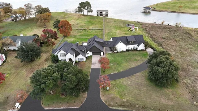 an aerial view of a house with a yard and lake view