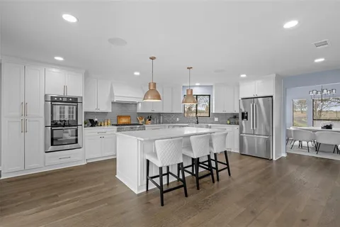 a kitchen with stainless steel appliances granite countertop a refrigerator and a stove top oven