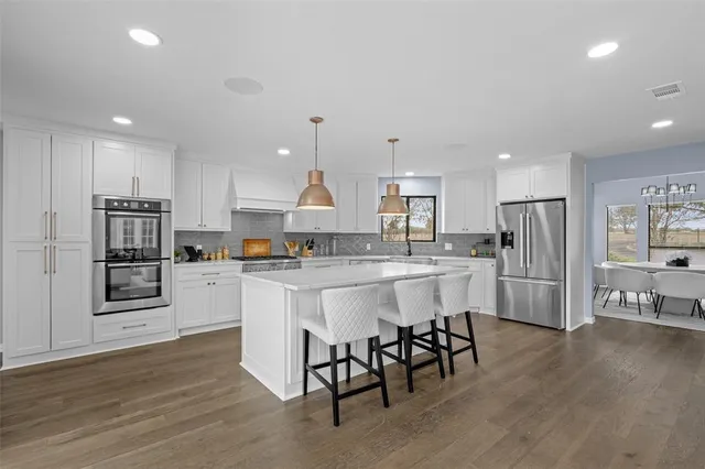 a kitchen with stainless steel appliances granite countertop a refrigerator and a stove top oven