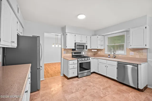 a kitchen with stainless steel appliances granite countertop a stove top oven a sink and dishwasher a refrigerator with wooden floor