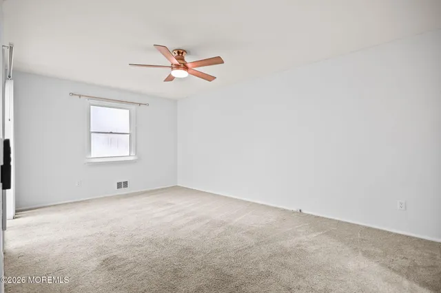 an empty room with a window and a fan