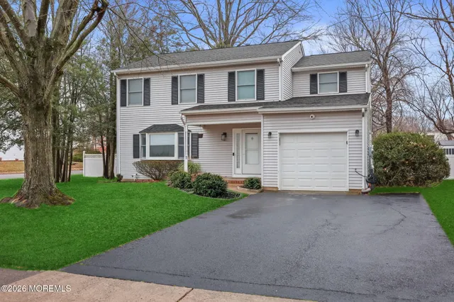 a front view of a house with a garden and trees