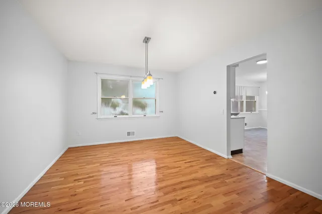 a view of an empty room with window and wooden floor