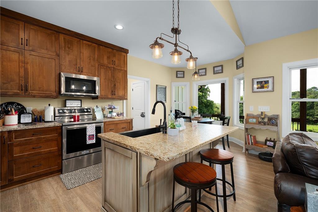 455 Poarch Farm Road Northeast Ranger, GA 30734 - Photo 50 of 93 a kitchen with stainless steel appliances granite countertop a stove top oven a sink a dining table and chairs with wooden floor