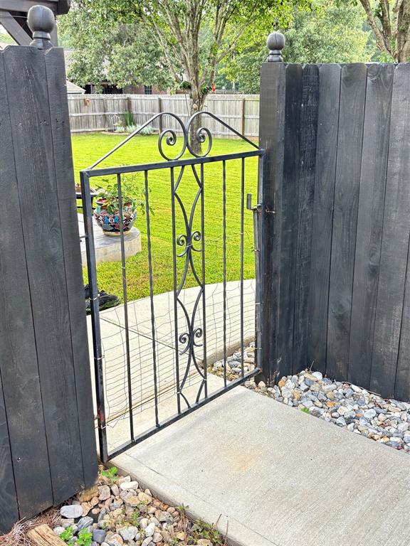 605 Jade Haughton, LA 71037 - Photo 30 of 34 Wrought iron gate providing access to a fenced backyard featuring a manicured lawn